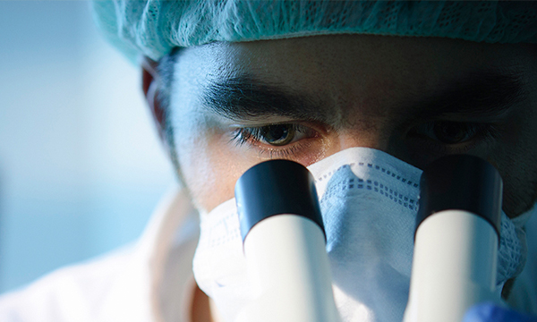 An image of individual looking through a microscope