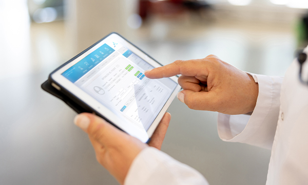 An aerial image of someone in a white coat viewing an iPad with data