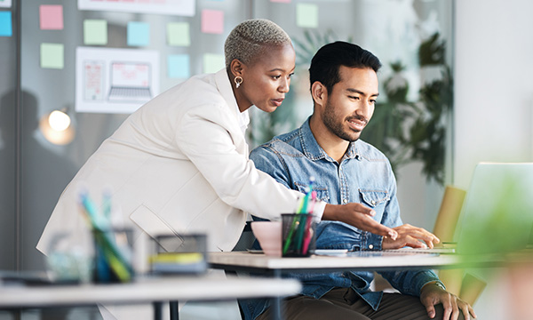 A woman and man collaborating next to a computer screen
